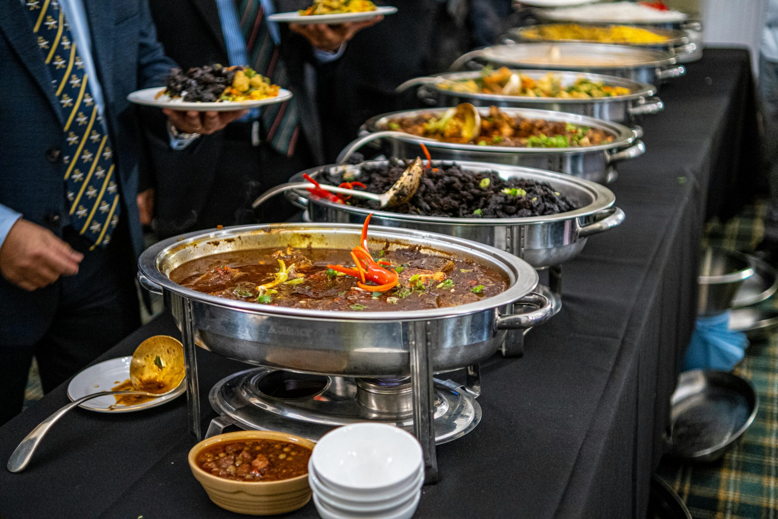 Elegant buffet display with various dishes served in warmers at a catered event.